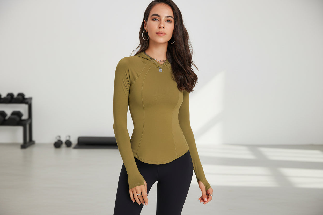 Woman wearing a green long-sleeve athletic top in a yoga studio