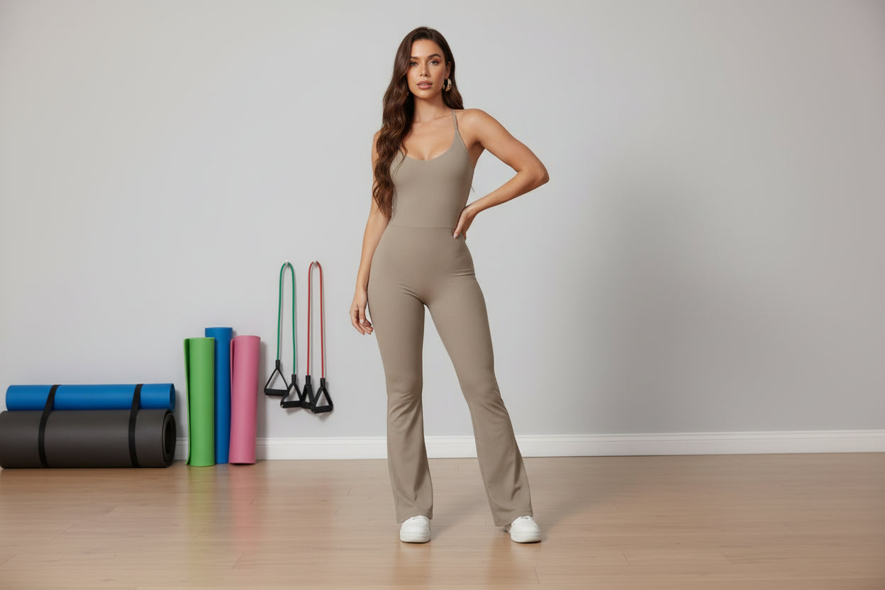 Woman wearing a beige jumpsuit in a gym with yoga mats and exercise bands