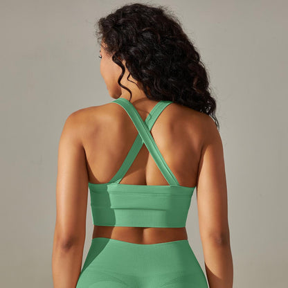 Woman wearing a green sports bra and leggings against a neutral background