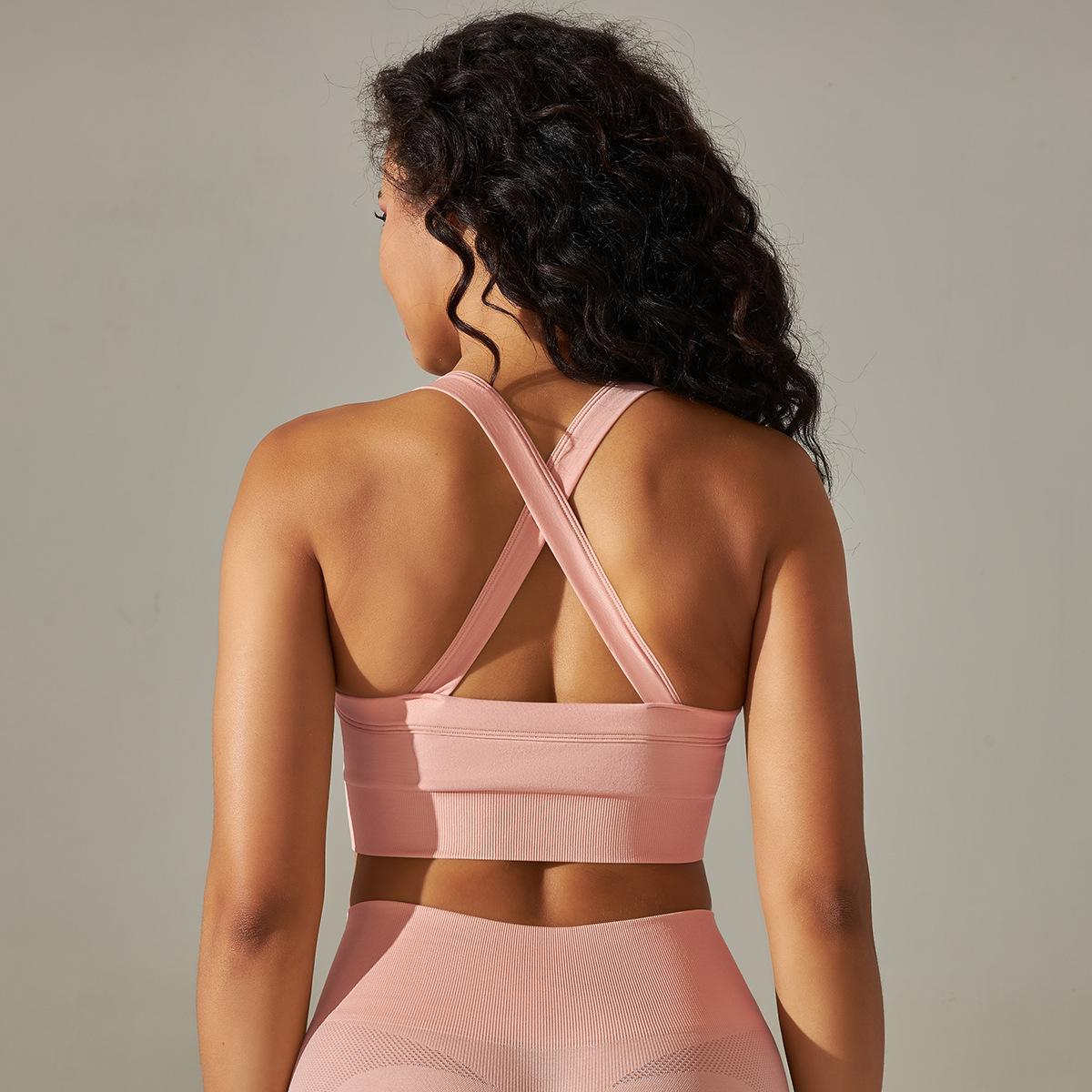 Woman wearing a pink sports bra and leggings against a neutral background