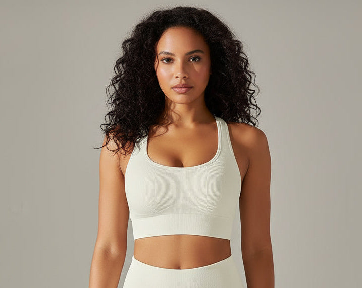 Woman wearing a white sports bra against neutral background