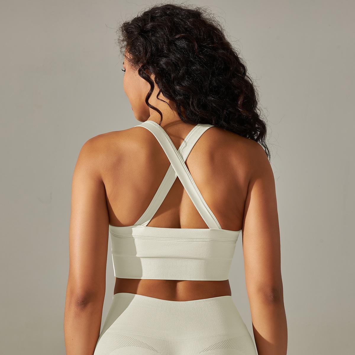 Woman wearing a white sports bra and leggings against a neutral background