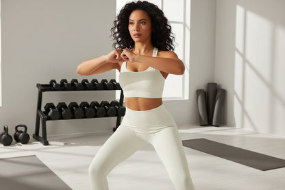 Woman wearing a white sports bra in a gym setting doing a squat