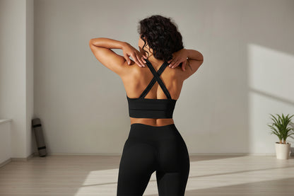 Woman wearing a black sports bra with criss-cross straps in a yoga studio